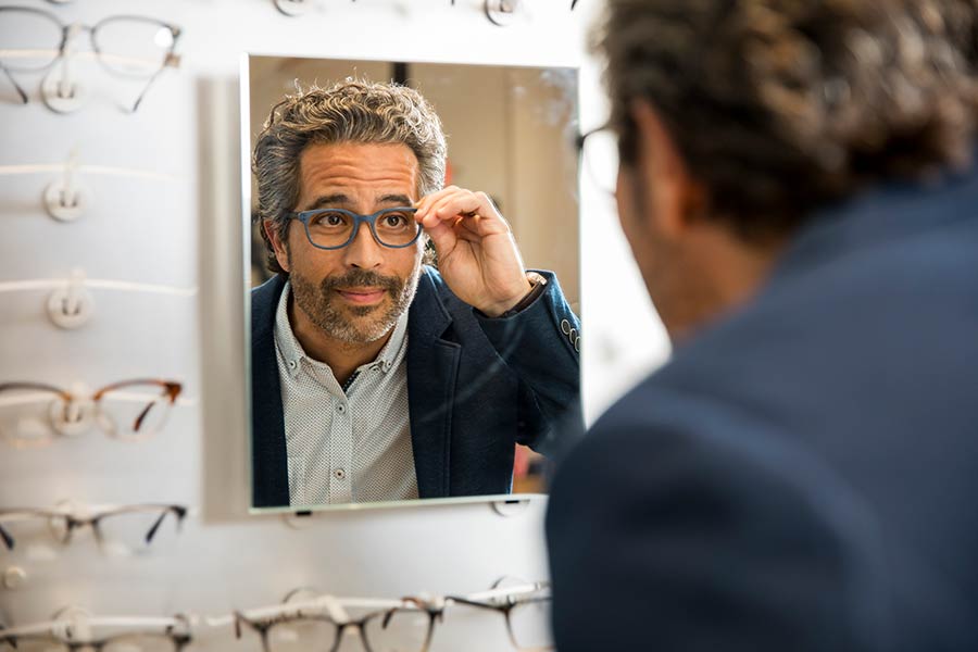 Man in a suit trying on glasses